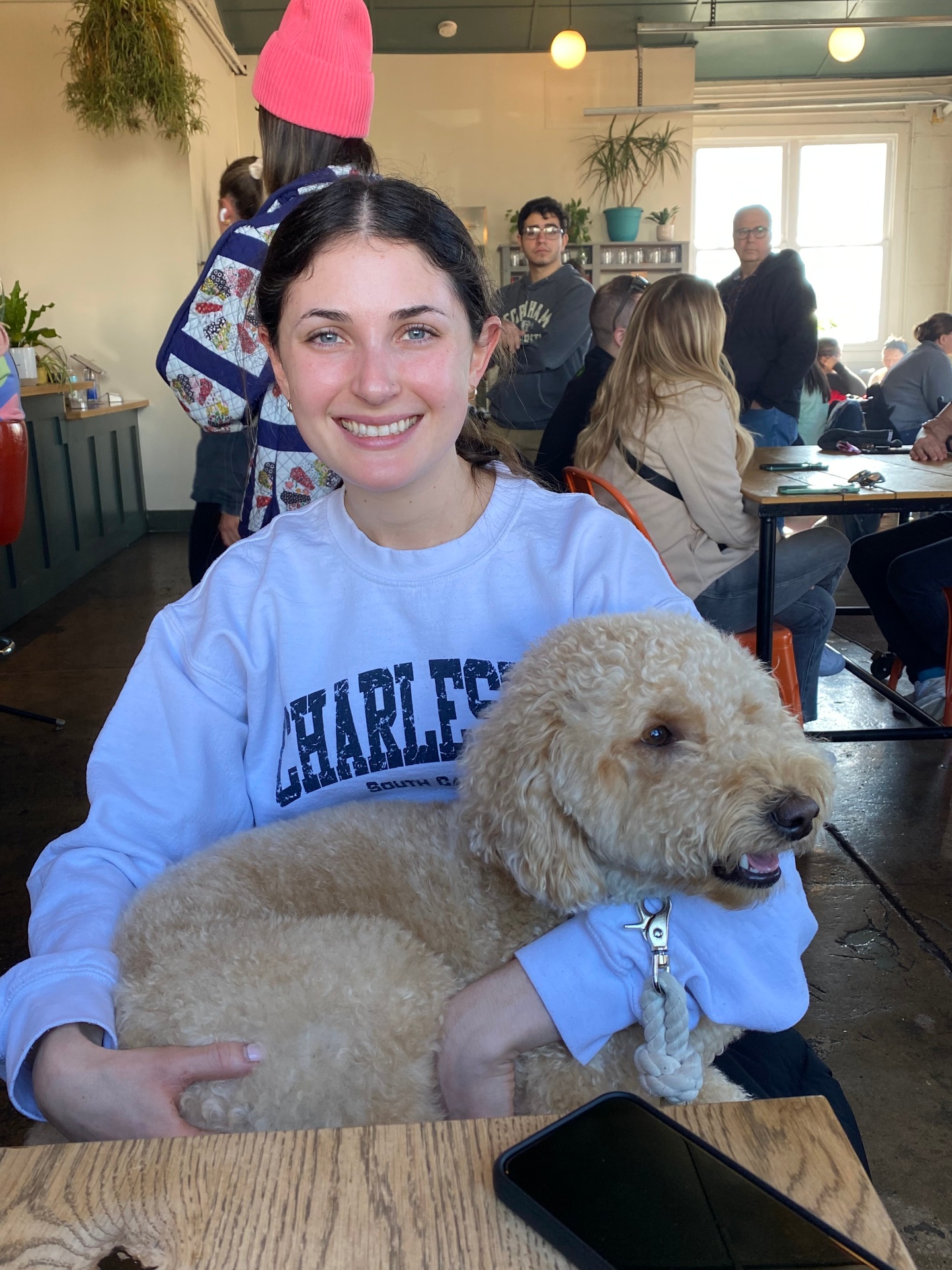 Ally cuddling a happy goldendoodle at a sunny café
