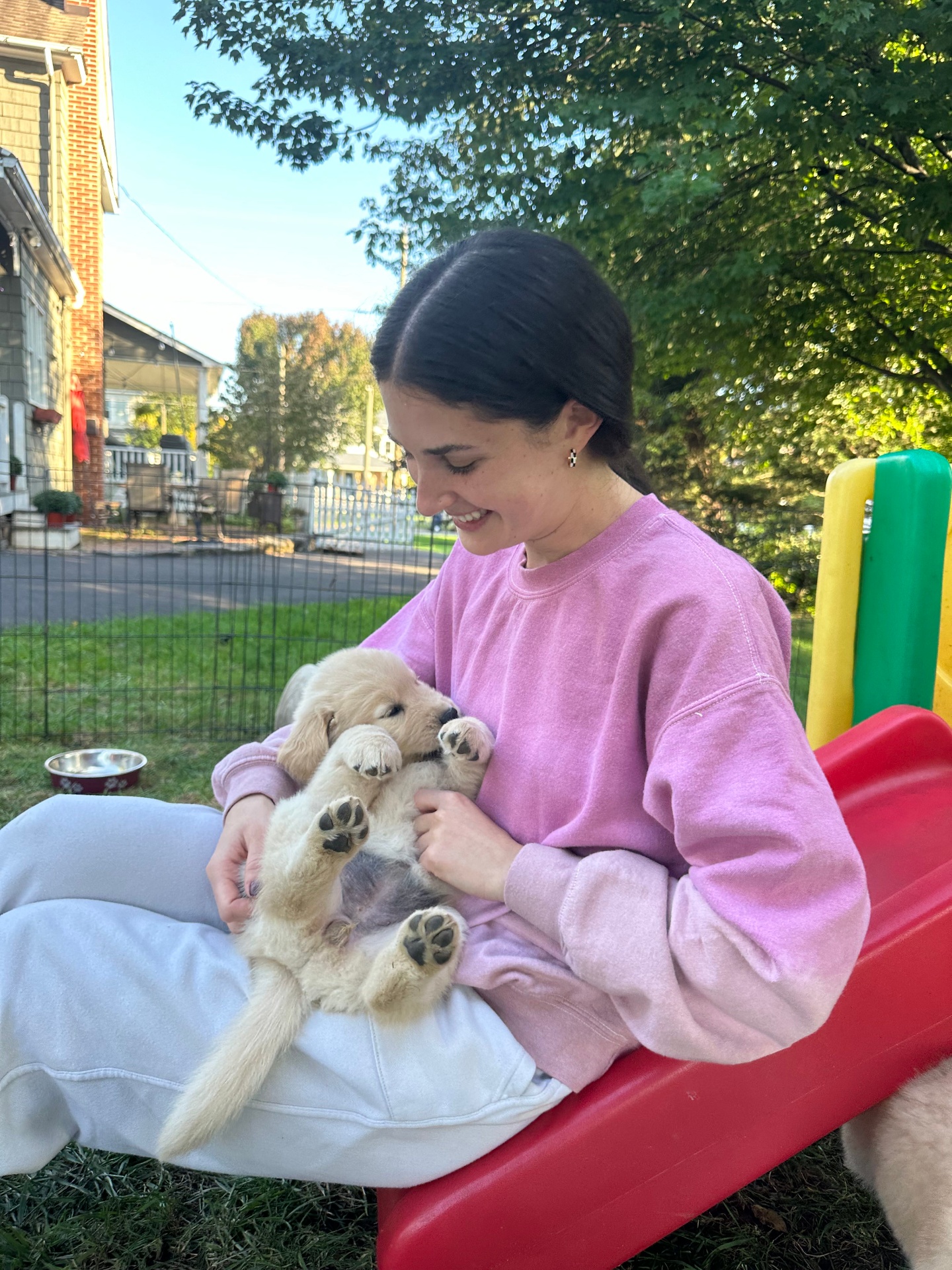 Ally cradling a tiny golden retriever puppy in her lap