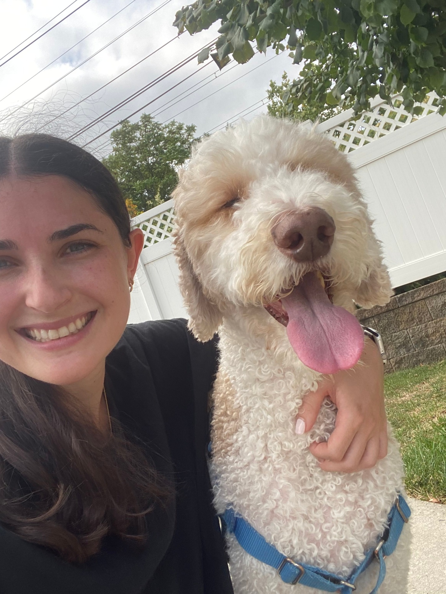 Ally smiling with a happy white doodle tongue out in the backyard